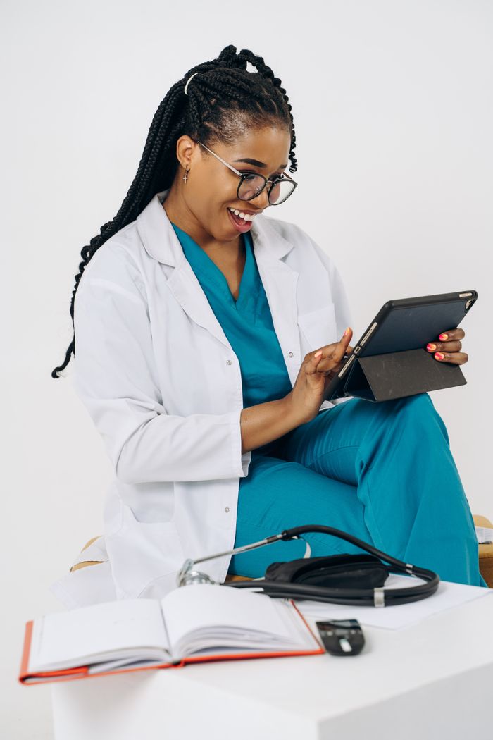 Mastering the First Impression: Your intriguing post title goes here Confident female doctor in scrubs using a tablet and smiling in a modern clinic setting.