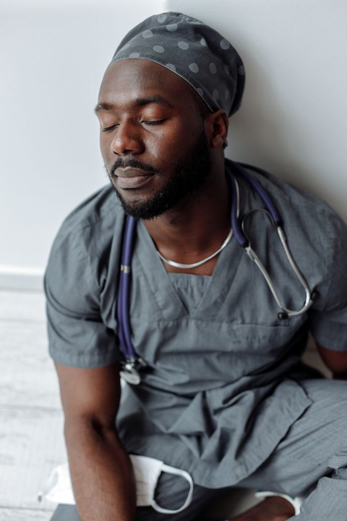 The Art of Drawing Readers In: Your attractive post title goes here A tired medical professional in gray scrubs resting with eyes closed in a hospital setting.