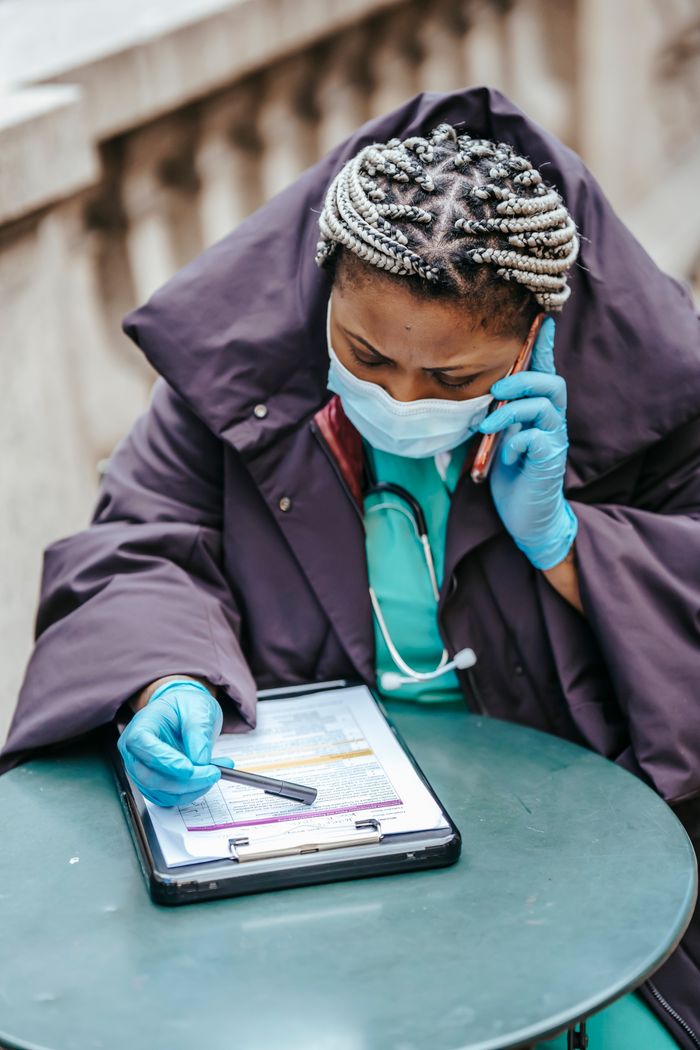 gallery-03 African American female doctor in uniform with document on clipboard speaking on cellphone in town